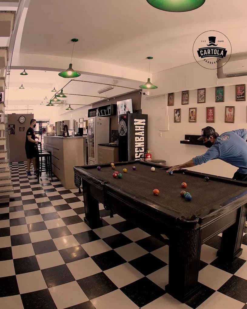 Mesa de sinuca, bar, piso xadrez e luminárias verdes no espaço da Cartola.